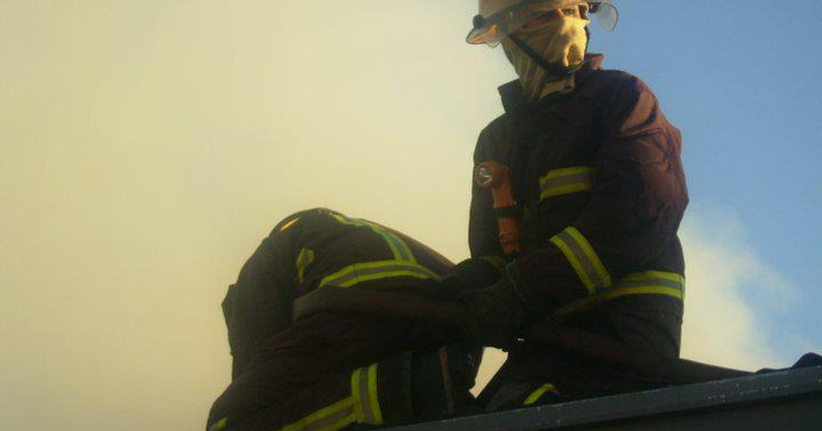 Bomberos voluntarios con equipo de protección trabajan sobre un techo durante un incendio en Fernando de la Mora, Central