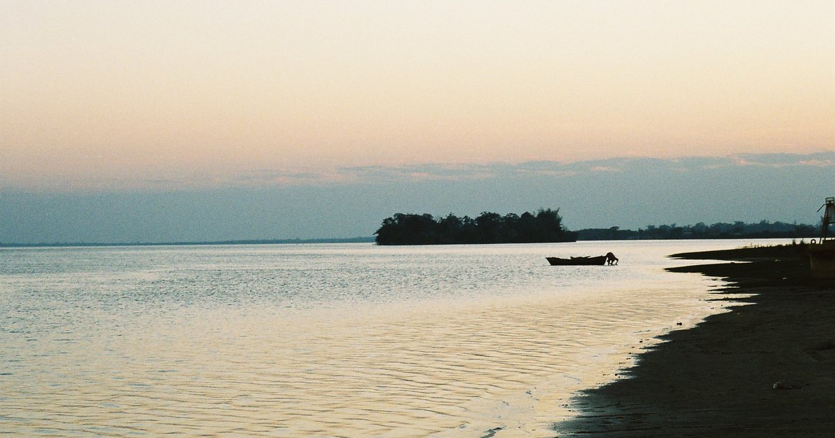 El río Paraná frente a la costa de Ayolas, en Misiones, al atardecer, con una lancha cerca de la orilla