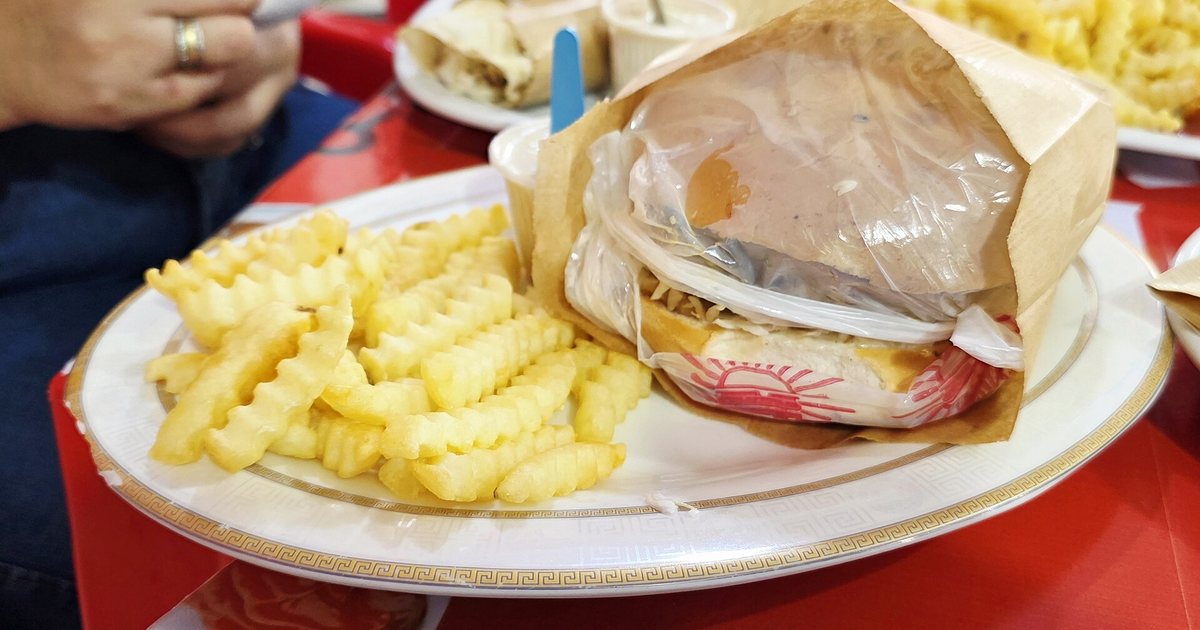 Hamburguesa envuelta en papel con papas fritas, servida en un local de comidas de Encarnación