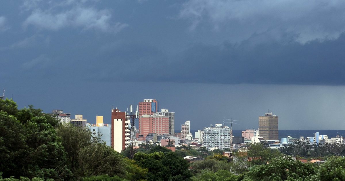 Edificios del centro de Asunción bajo un cielo oscuro de tormenta, vistos por encima de una arboleda
