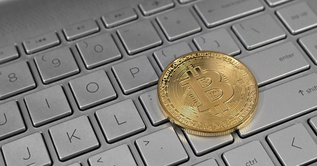 Moneda física con el símbolo de bitcoin sobre el teclado de una computadora