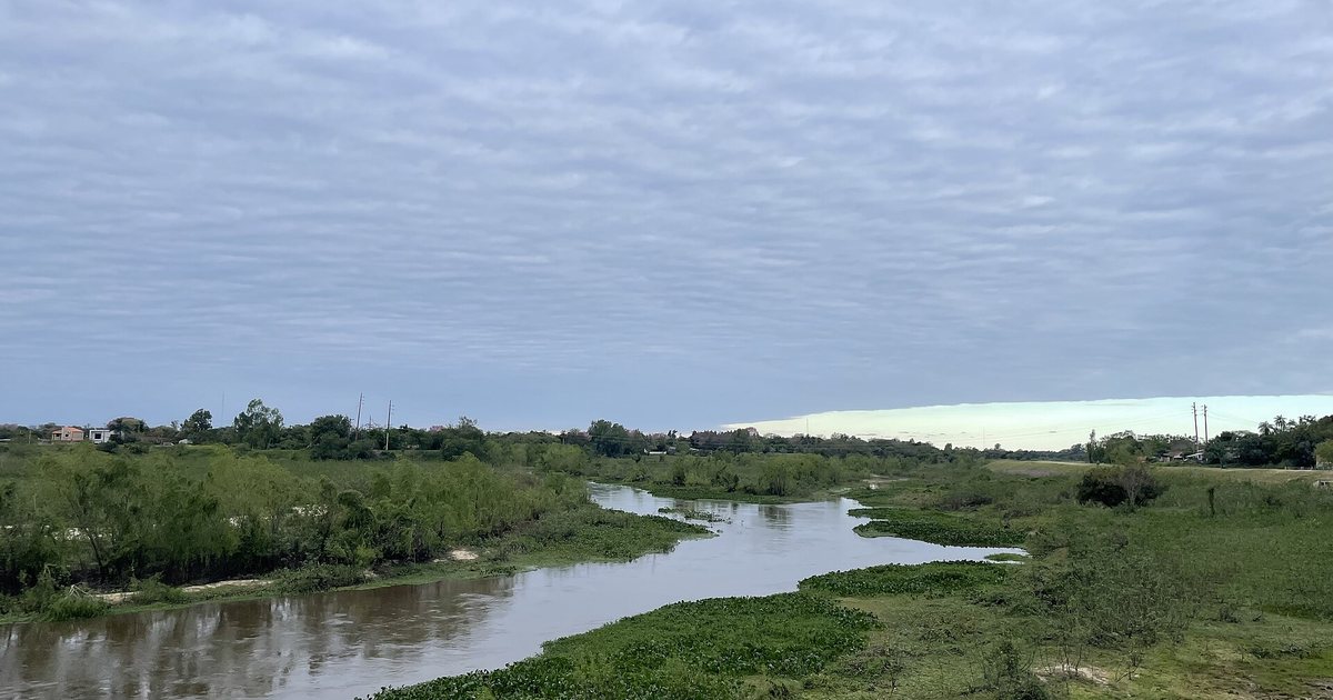Arroyo Ñeembucú bajo un cielo cubierto, visto desde un terraplén en Pilar