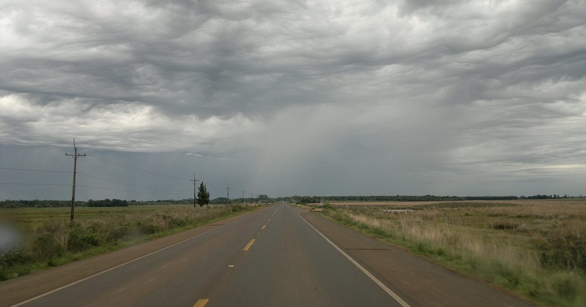 Nubes de tormenta sobre una ruta en General Delgado, Itapúa, con campos a los costados
