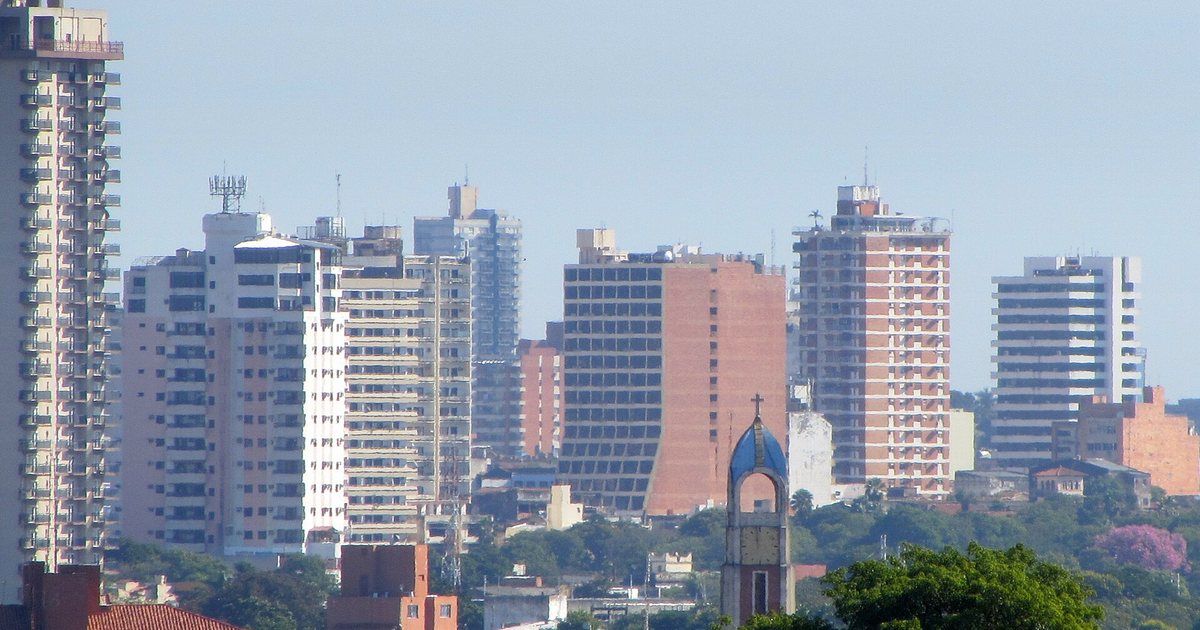 Edificios del centro de Asunción y un campanario entre los árboles, vistos a la distancia