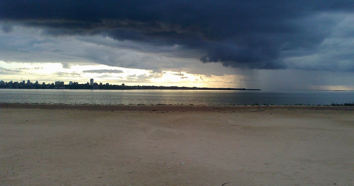 Nubes de tormenta y una cortina de lluvia sobre el río Paraná, vistas desde la playa de Encarnación, en Itapúa