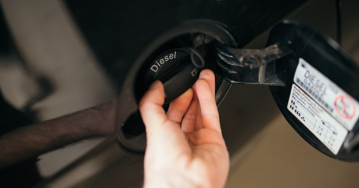 Una mano abre la tapa del tanque de un vehículo diésel para cargar gasoil