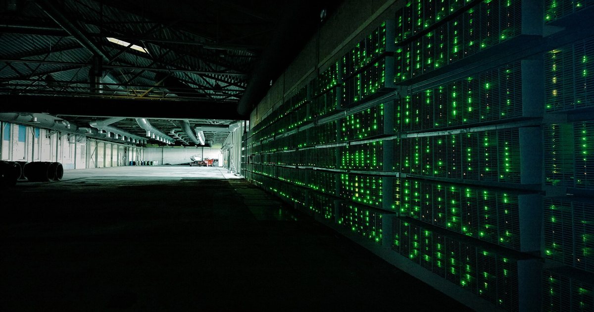 Hileras de equipos de minería de criptomonedas encendidos dentro de un galpón