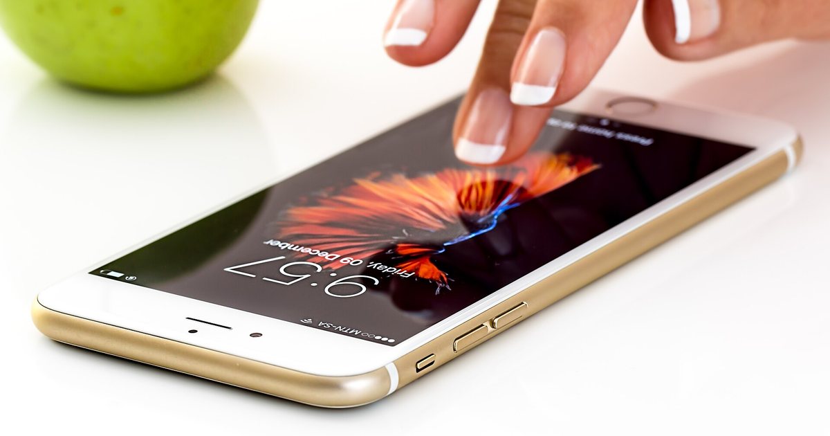 Una persona toca la pantalla de un teléfono inteligente apoyado sobre una mesa